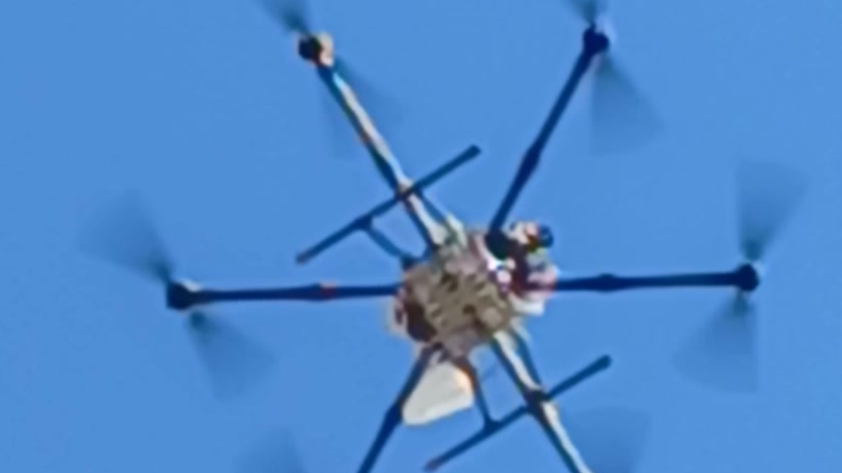 Hexacopter drone overhead during test campaign, IceConeFeed S-Band antenna visible transmitting toward indoor receiver