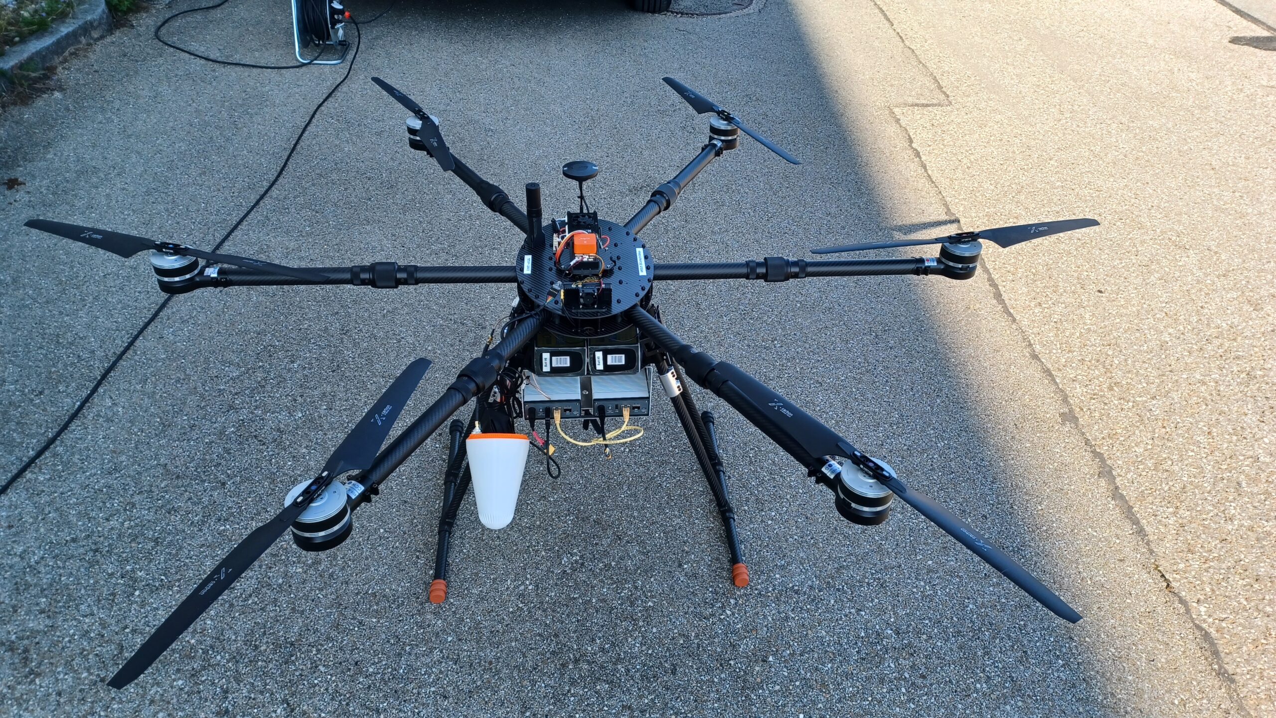 Hexacopter drone on ground viewed from above with custom IceConeFeed S-Band antenna mounted underneath