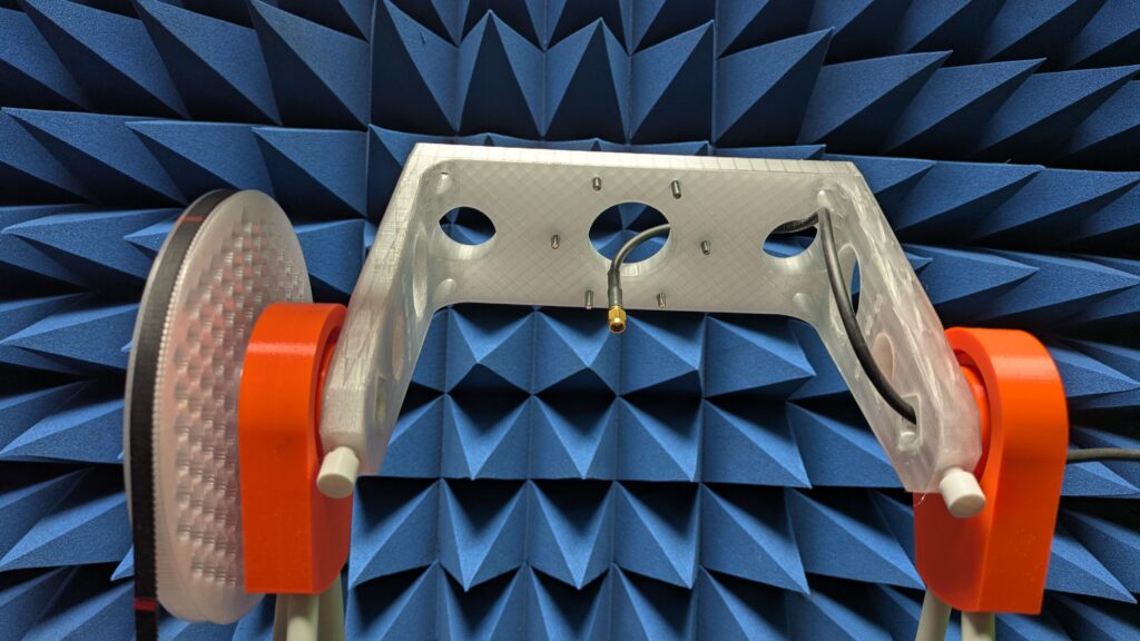 Photo of the C-bracket installed in the Anechoic Test Field with an antenna mounted in the centre aperture and the SMA feedline dropping out of the underside.